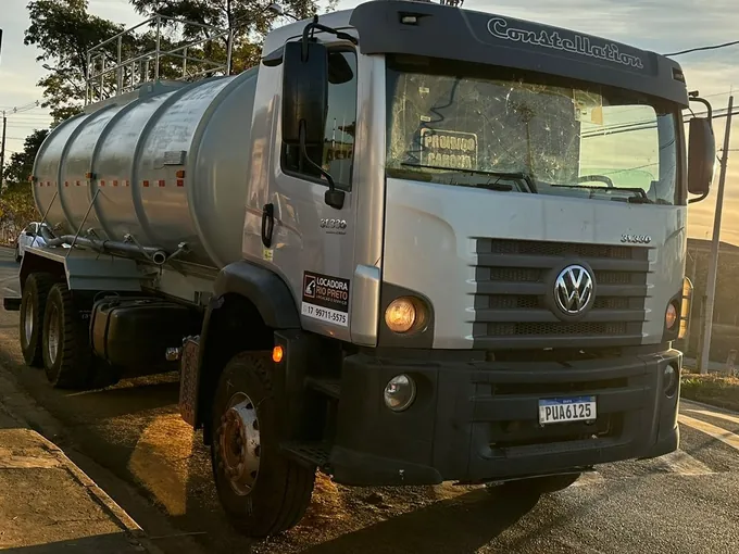 Caminhão pipa Volkswagen Constellation traçado da Locadora Rio Preto, visto de frente num pátio de terra