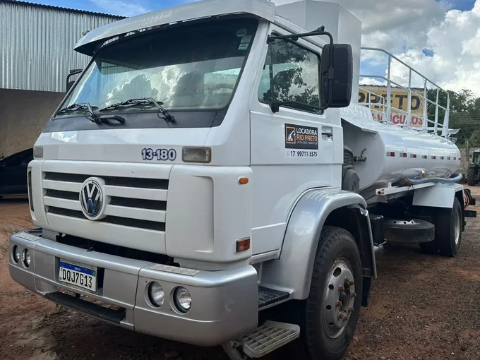 Caminhão pipa Volkswagen 13-180 prata da Locadora Rio Preto, com tanque de aço, em frente a um galpão